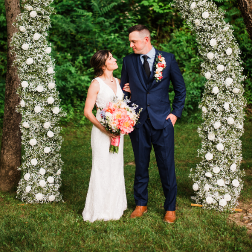 Bride and groom posing in front of a flower wedding arch